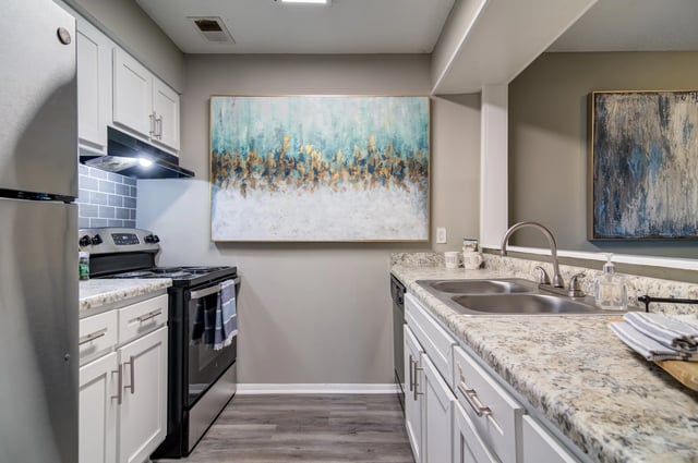 Modern kitchen with stainless steel appliances, white cabinets, and granite countertops.