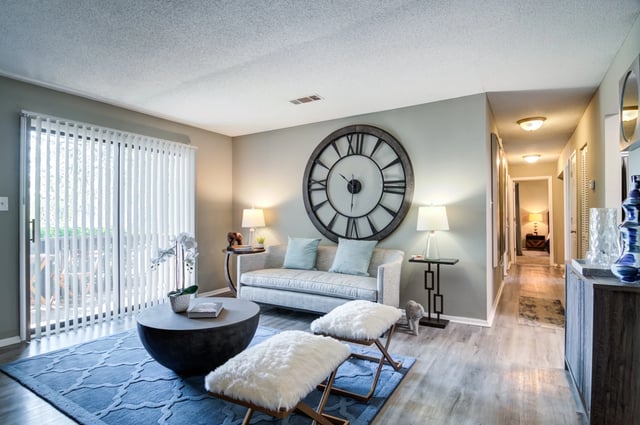 Living room with large wall clock, sofa, coffee table, and sliding glass door.