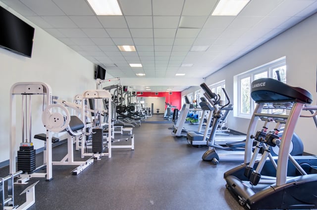 Fitness center gym with treadmills, ellipticals, and weight machines.