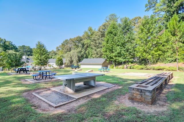 Outdoor recreation area with a ping pong table, picnic tables, and horseshoe pits.