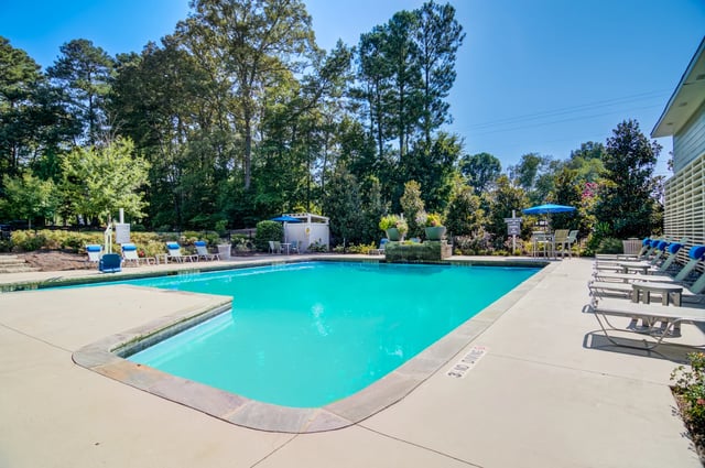 Outdoor swimming pool with lounge chairs and umbrellas.