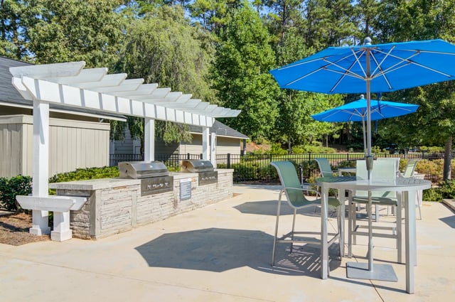 Outdoor grilling area with built-in grills, seating, and umbrellas.