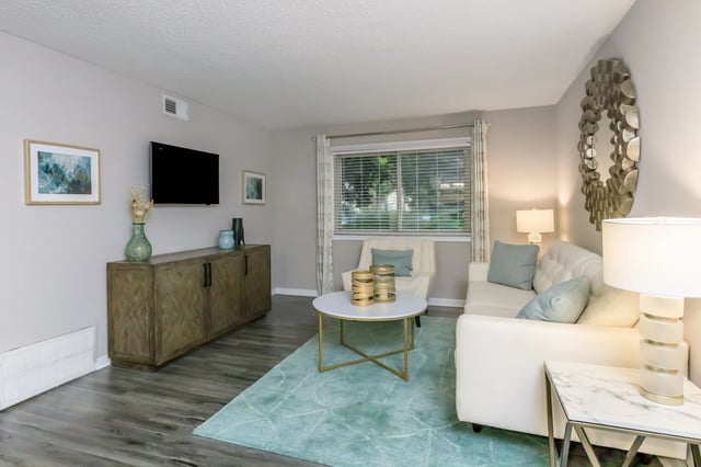 Living room with white sofa, coffee table, TV, and sideboard.