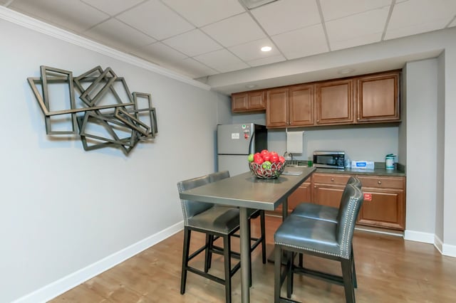 Kitchenette area with a high-top table and chairs, refrigerator, microwave, and cabinetry.