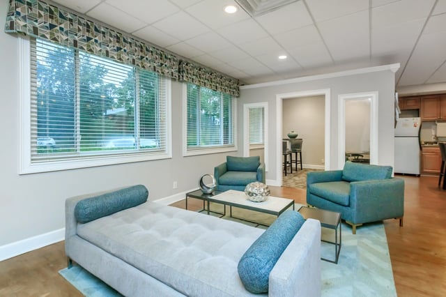 Modern lounge area with grey chaise, teal armchairs, and coffee table.