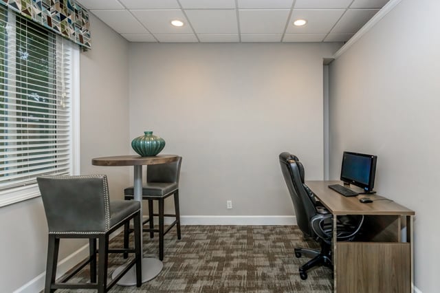 Business center with a desk, computer, and a high-top table with two chairs.