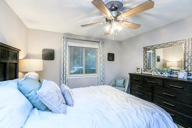 Bedroom with a king-size bed, dresser, and ceiling fan.