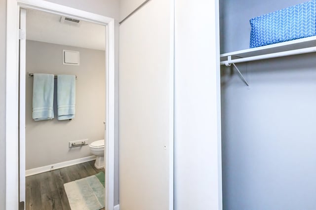 View of a bathroom with two blue towels hanging on a rack and a toilet.