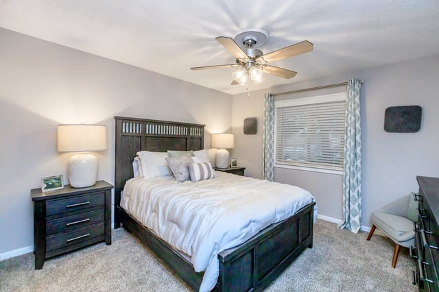 Modern bedroom with a king-size bed, nightstands, and a ceiling fan.