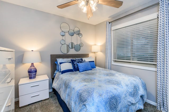 Bedroom with a queen-size bed, nightstand, dresser, and ceiling fan.