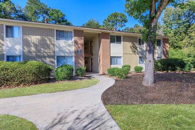 Exterior of apartment building with a winding sidewalk and lush landscaping.