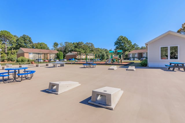 Outdoor recreational area with picnic tables, ping pong table, and playground.