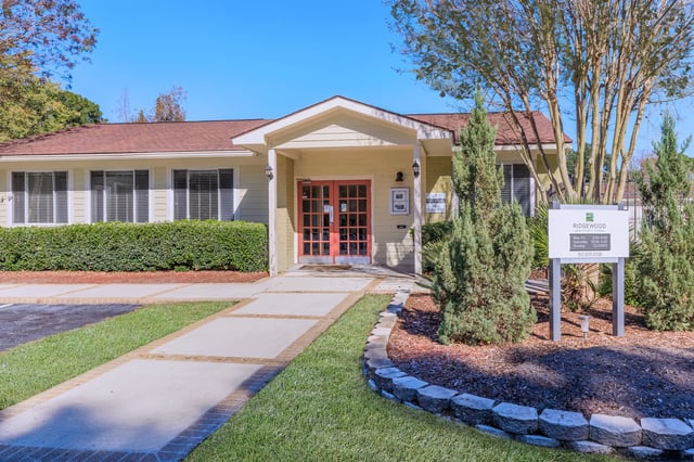 Exterior of the building entrance at Ridgewood Apartments with a sign listing hours.