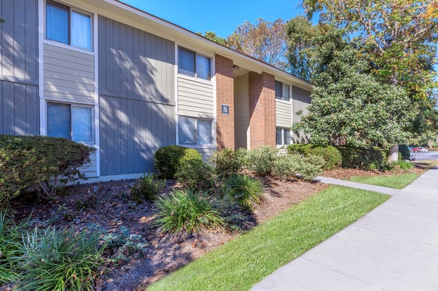 Exterior view of apartment building with manicured landscaping and sidewalk.