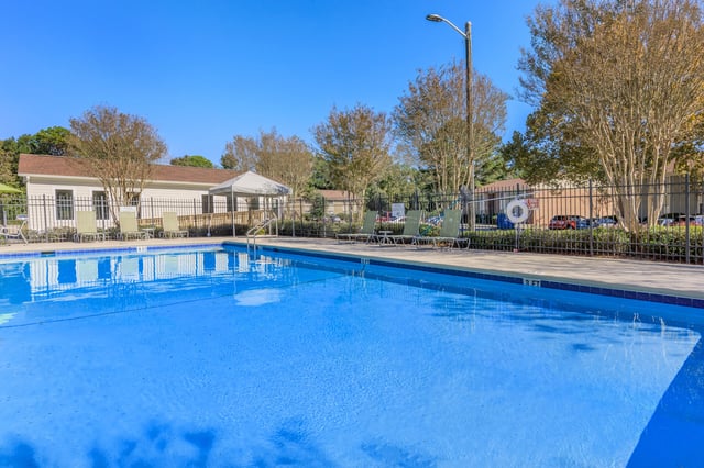 Outdoor swimming pool with lounge chairs and a building in the background.