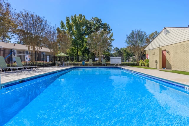 Outdoor swimming pool with lounge chairs and umbrellas.