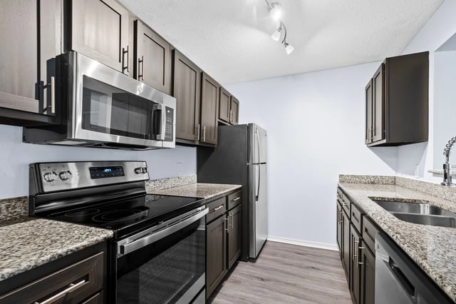Modern kitchen with dark wood cabinets, stainless steel appliances, and granite countertops.