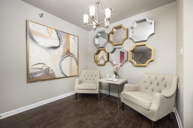 Cozy seating area with two armchairs, a small table with a book and coffee cup, and decorative mirrors.