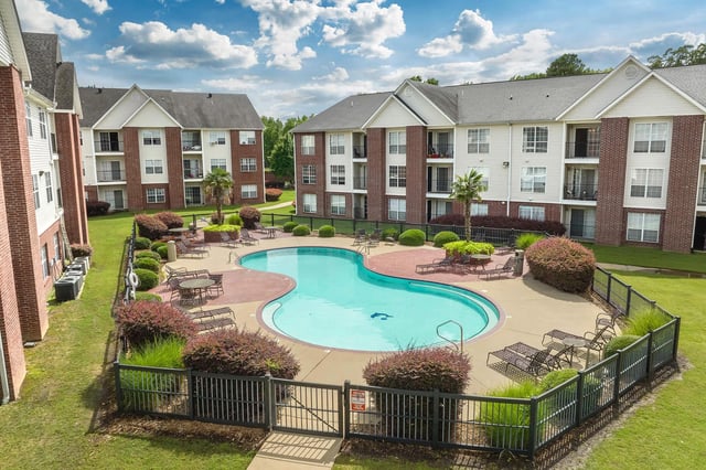 Apartment complex outdoor swimming pool with lounge chairs and tables.
