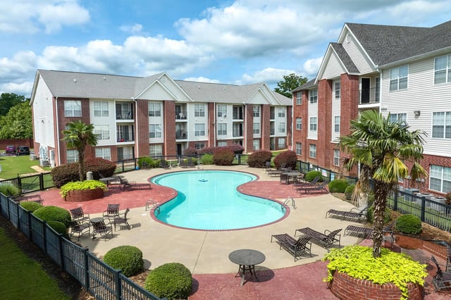 Outdoor swimming pool and lounge area surrounded by apartment buildings.