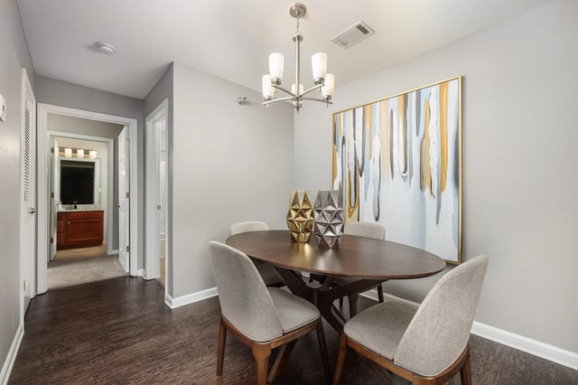 Dining area with oval table, four chairs, and abstract wall art.