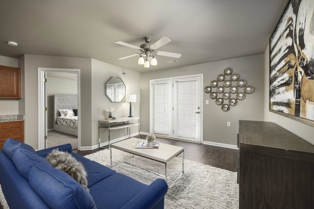 Living room with a blue sofa, coffee table, and view into bedroom.