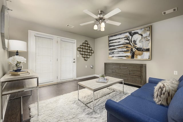Living room with blue couch, coffee table, dresser, and abstract art.