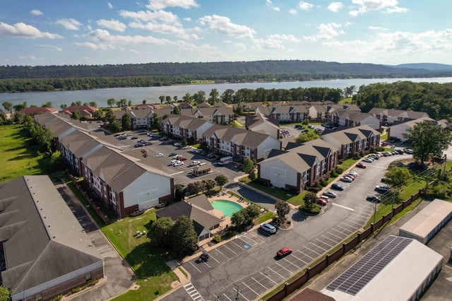 Aerial view of apartment complex with pool and lake in background.