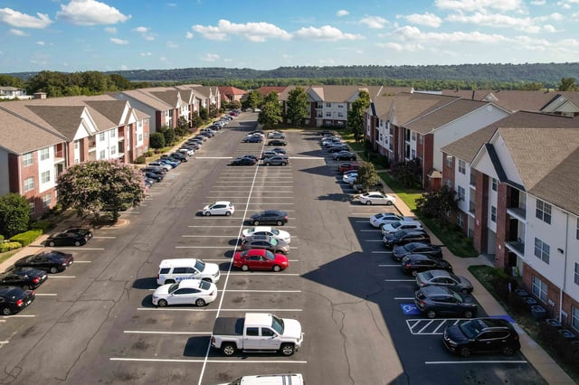 Aerial view of apartment buildings with a large parking lot filled with cars.