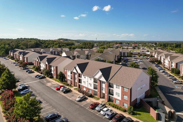 Aerial view of apartment buildings with parking lots and trees.