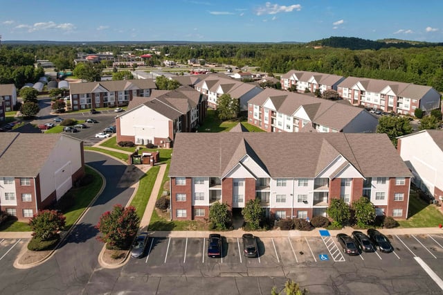 Aerial view of apartment buildings with parking lots and landscaping.