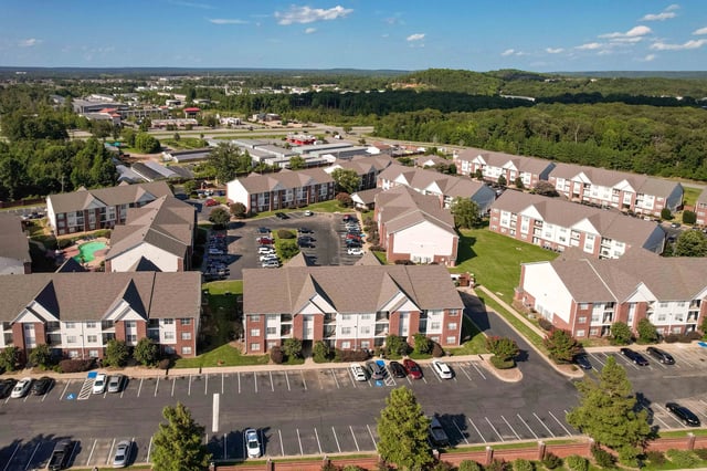 Aerial view of a multifamily property with multiple buildings, parking lots, and a pool.