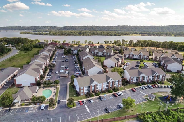 Aerial view of apartments with a swimming pool and a river in the background.
