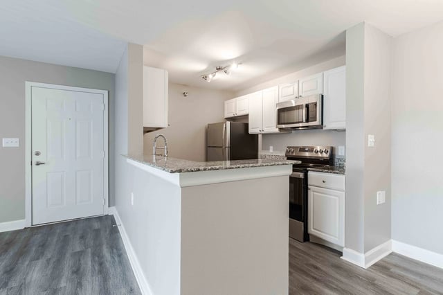 Kitchen with white cabinets, granite countertops, stainless steel appliances, and a door.
