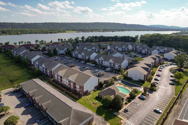 Aerial view of apartment buildings and a swimming pool with a lake in the background.