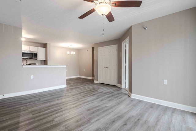 Living room and kitchen area with wood-look flooring and a ceiling fan.