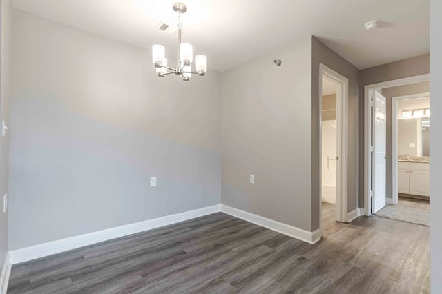 Empty dining room with wood-look flooring and chandelier.