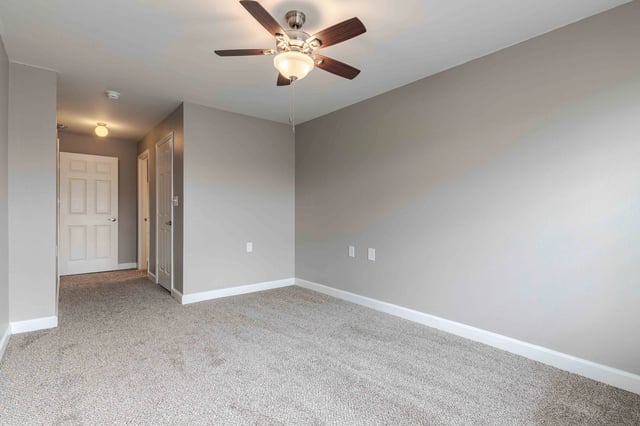 Bedroom with a ceiling fan and neutral gray walls.