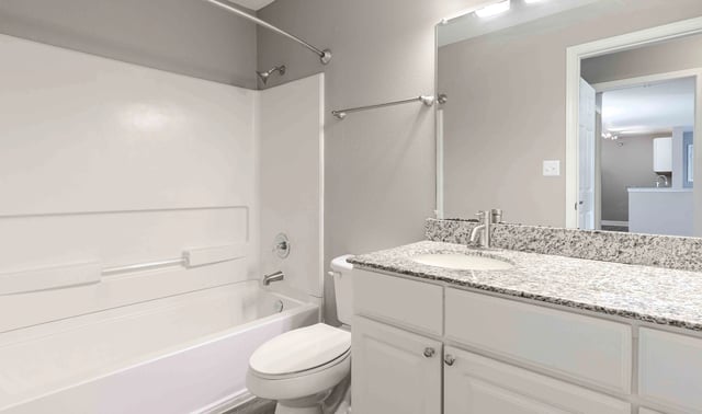 Modern bathroom with a white tub, shower, toilet, and a vanity with a granite countertop and a stainless steel faucet.