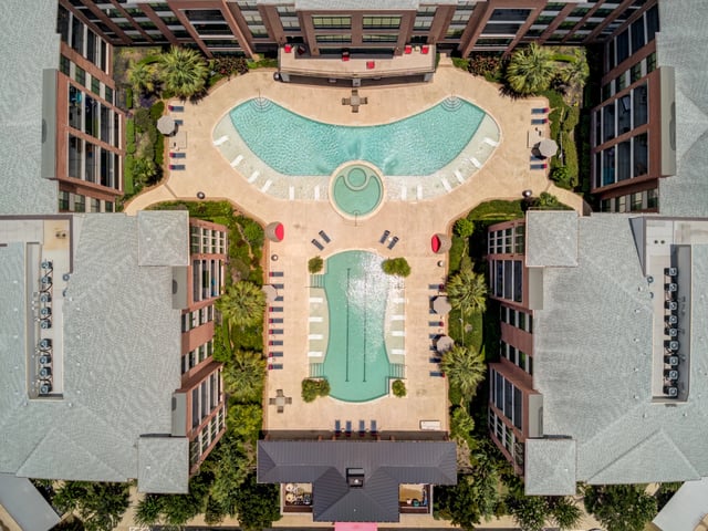 Aerial view of a resort-style swimming pool and surrounding apartment buildings.