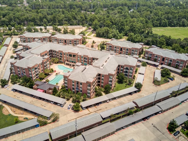 Aerial view of apartment buildings surrounding a courtyard with a pool.
