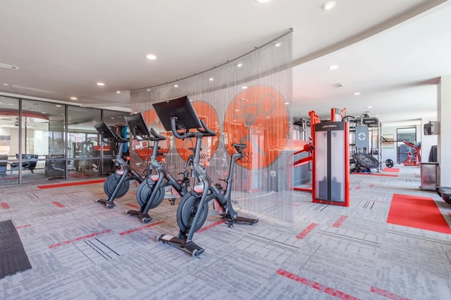 Modern apartment complex gym with Peloton bikes and weight machines.