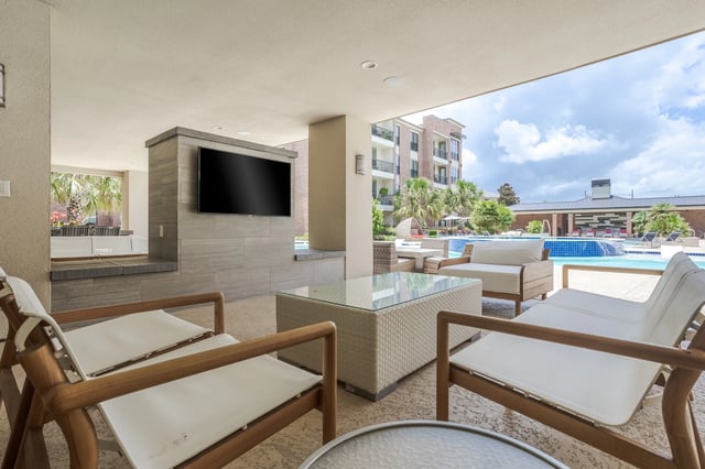 Outdoor seating area with a TV overlooking the pool.