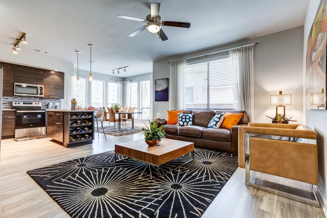 Spacious living room with a leather sofa, coffee table, and open-concept kitchen.