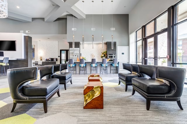 Modern lounge area with black leather sofas, a unique coffee table, and bar seating with pendant lights.
