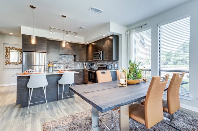 Modern kitchen and dining area with stainless steel appliances, dark wood cabinets, and a large dining table.