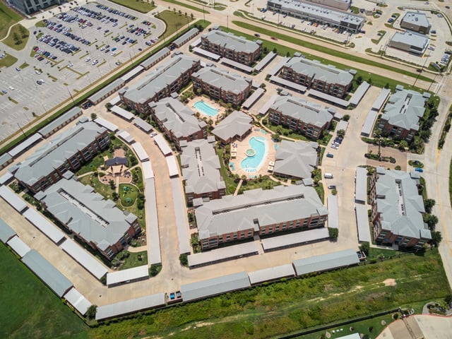 Aerial view of apartment buildings with a pool and courtyard.