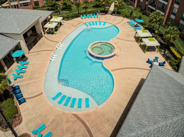 Aerial view of a resort-style swimming pool and spa area with lounge chairs and cabanas.