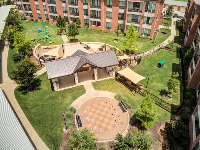 Outdoor amenities including a playground, covered pavilion, giant chess board, and fenced dog run.