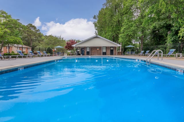 Swimming pool and lounge chairs with a building in the background